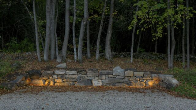 After: Parking/turn-around area defined by stone wall built with stones from the site and clear view of existing farm wall in the distance. Landscape lighting is discreet to help with parking at night.